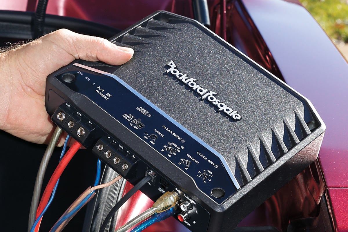 Car amplifier installed in trunk powering subwoofers for deep bass