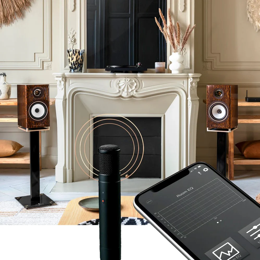 Room EQ microphone measuring speaker calibration in a modern living room with bookshelf speakers and tuning app